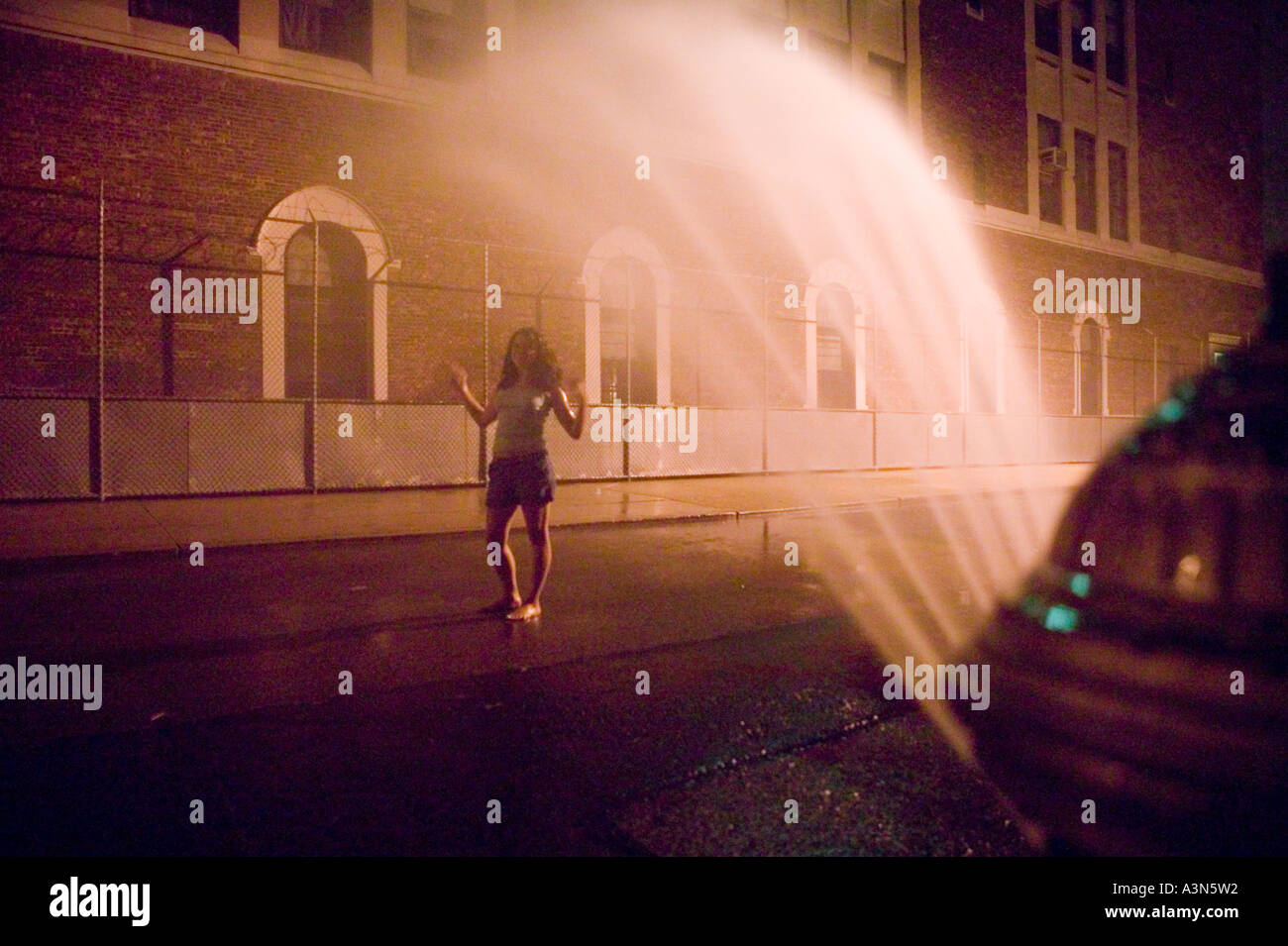 A Young Woman Enjoys The Spray Of An Open Fire Hydrant In A Street Of Stock Photo Alamy