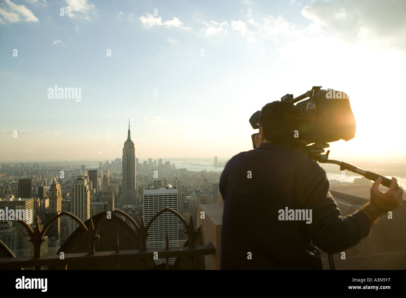 TV crew shoots footage of Midtown Manhattan and Empire State Building from viewing area atop Rockefeller Center in New York City Stock Photo