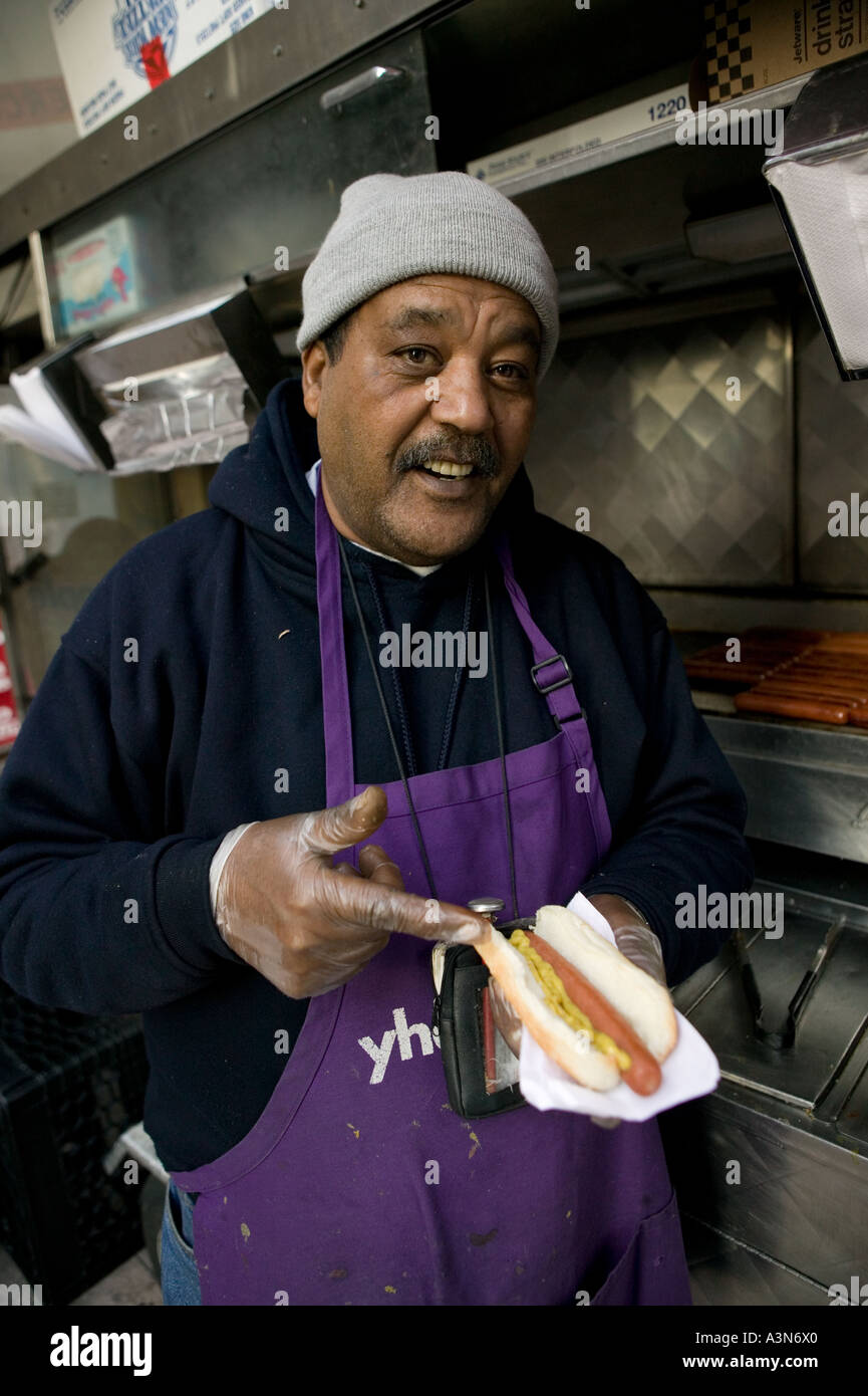 Middle eastern man selling hot dogs by his cart on 6th Avenue on New