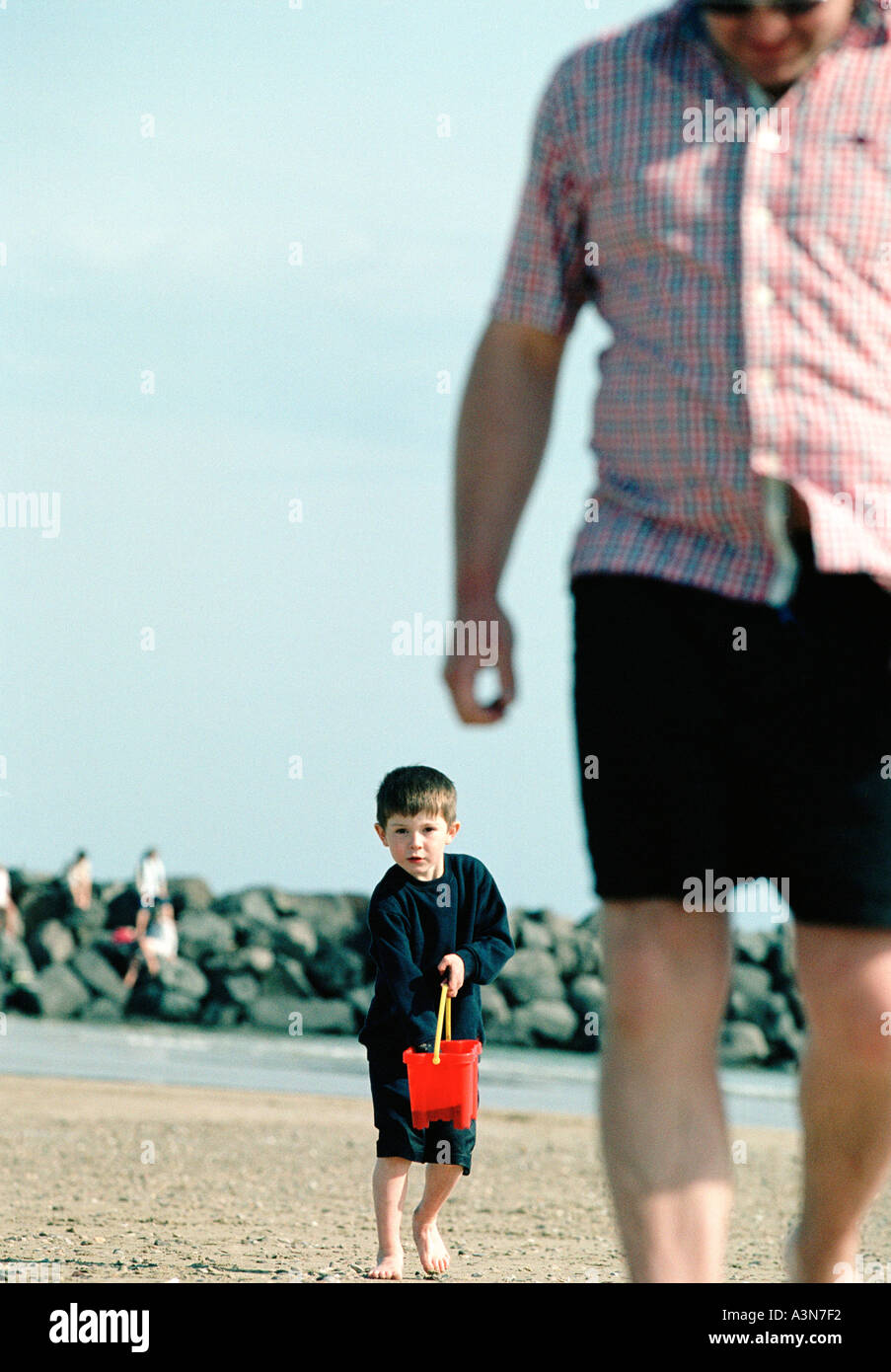 child holding red bucket and father on the beach dad daddy play summer