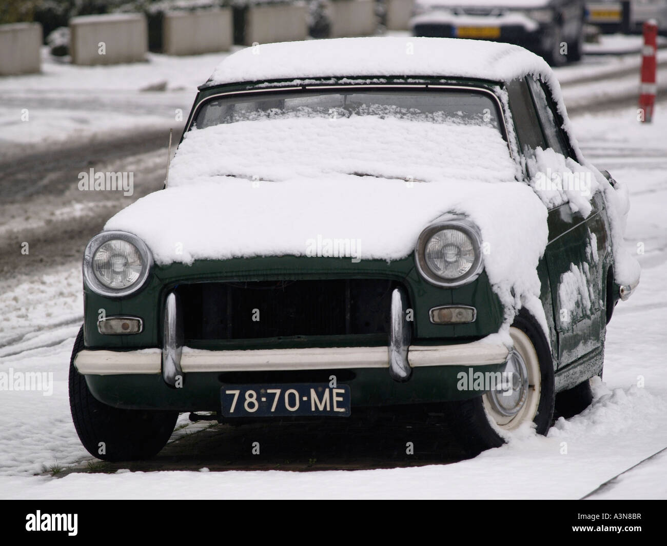 Classic car British racing green Triumph Herald covered in snow Dutch license plate Breda the Netherlands Stock Photo