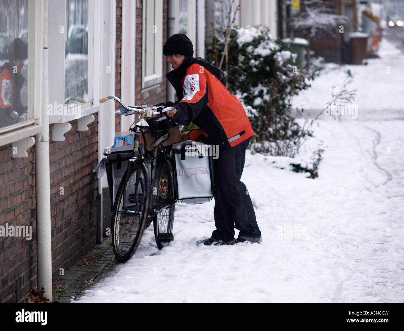 TNT mailwoman lady working in adverse conditions bad foul winter weather Breda the Netherlands Stock Photo