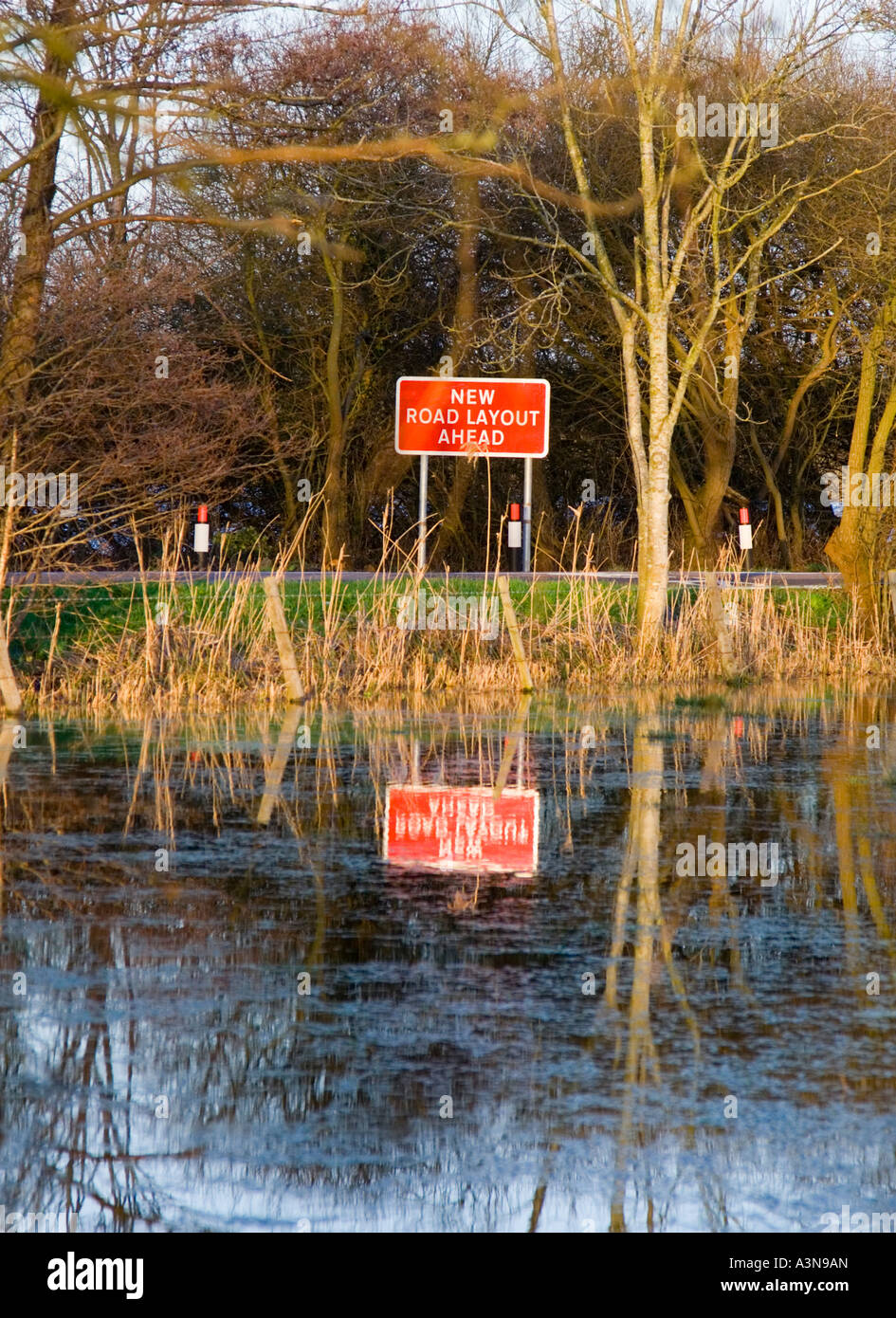 Road sign. New road layout ahead, reflected in a flooded field next to the road. Dorset. UK. Stock Photo