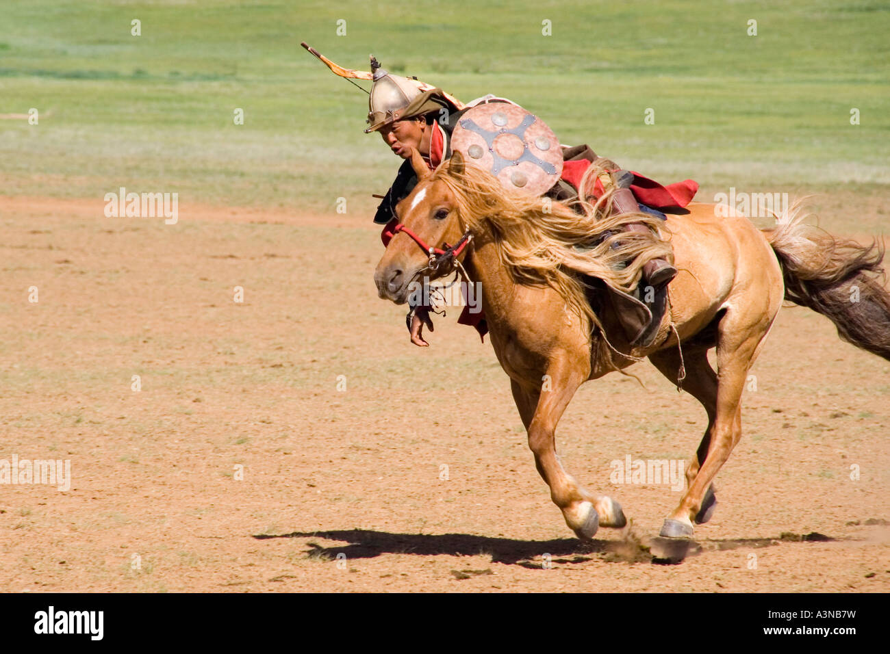 Armed Mongolian warrior on horseback leaning over to pick up his dropped spear Stock Photo
