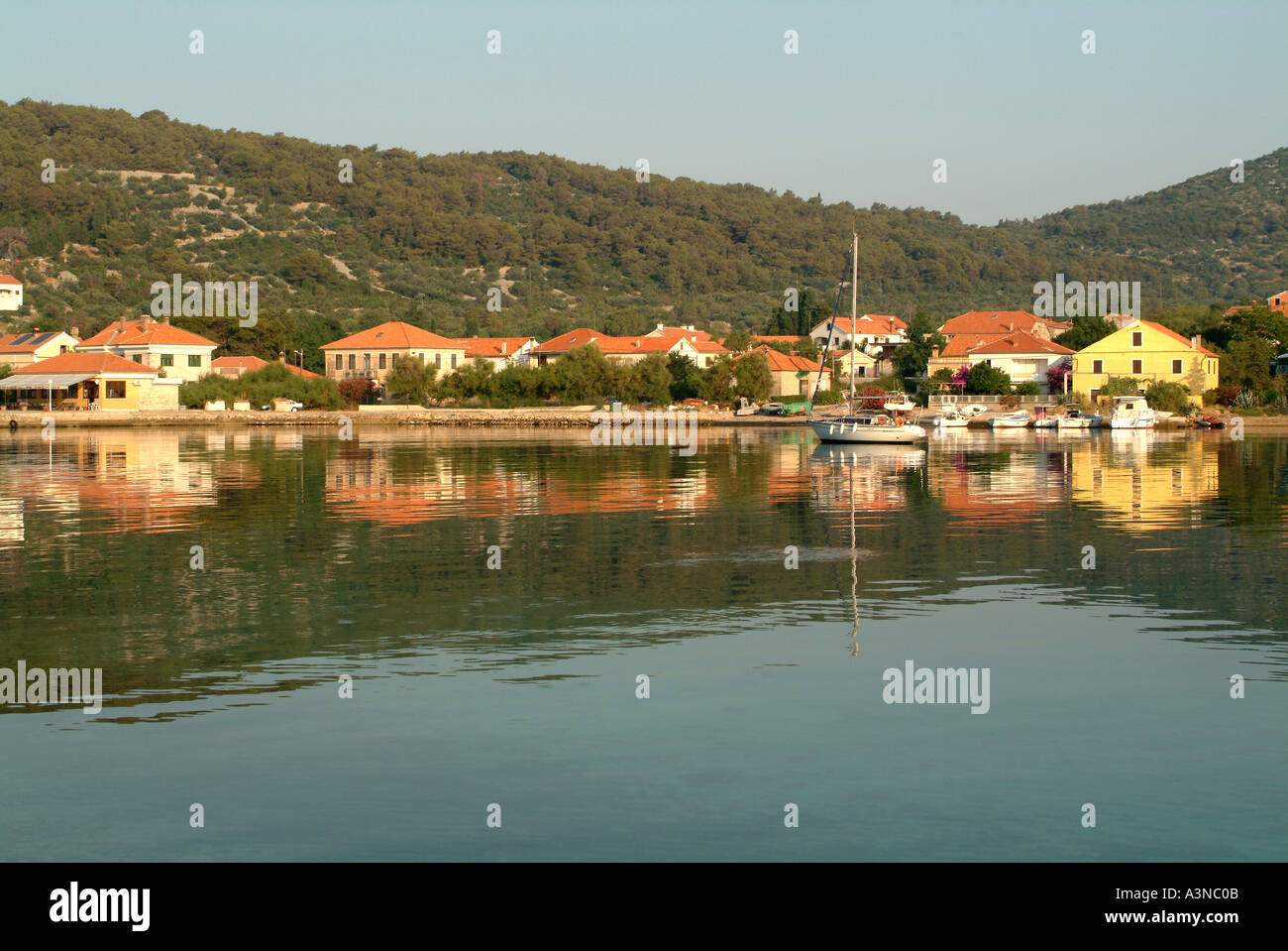 Houses and Yacht Reflected in Water at Veli on Otok Iz Island Croatia Stock Photo