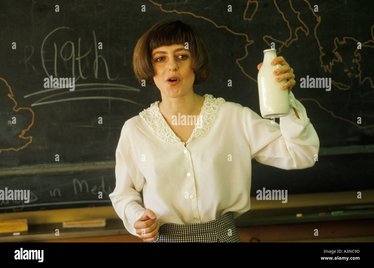 Secondary School 1990s UK. Female domestic science teacher Greenford High School Middlesex, holding up a glass pint milk bottle 1990 UK HOMER SYKES Stock Photo