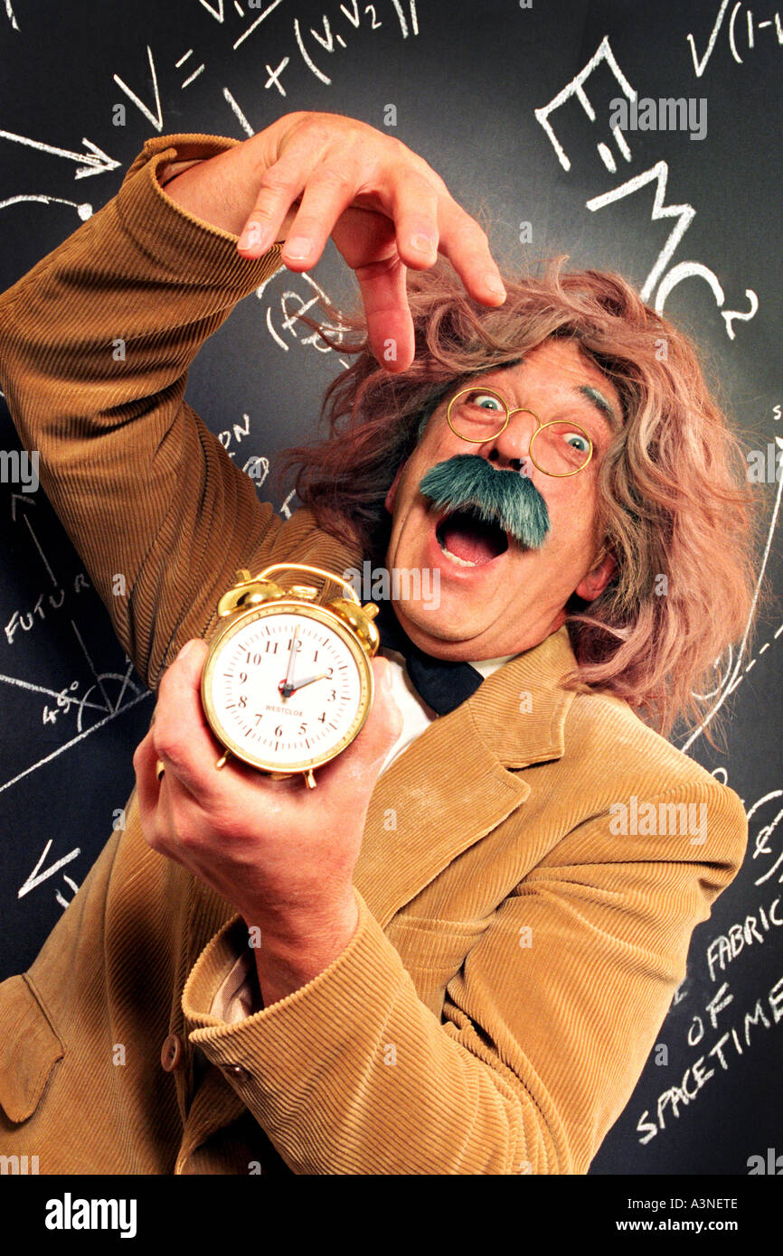 Clock being held by mad professor looking like Einstein with E=MC2 on blackboard with equations about time, time travel & space Stock Photo
