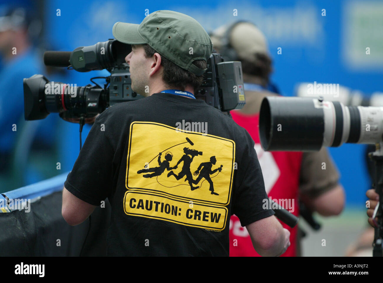 Television Cameraman with film crew T shirt at tennis match Stock Photo