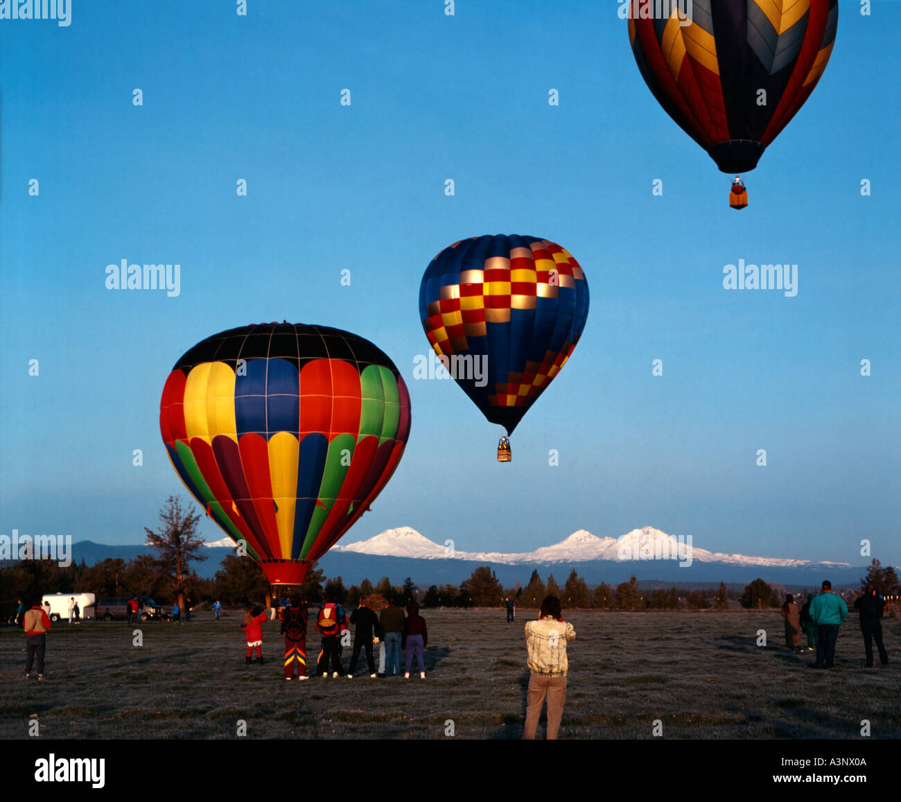 Hot air balloons lift off in early morning at Redmond in Central Oregon with the Cascade mountains as backdrop Stock Photo