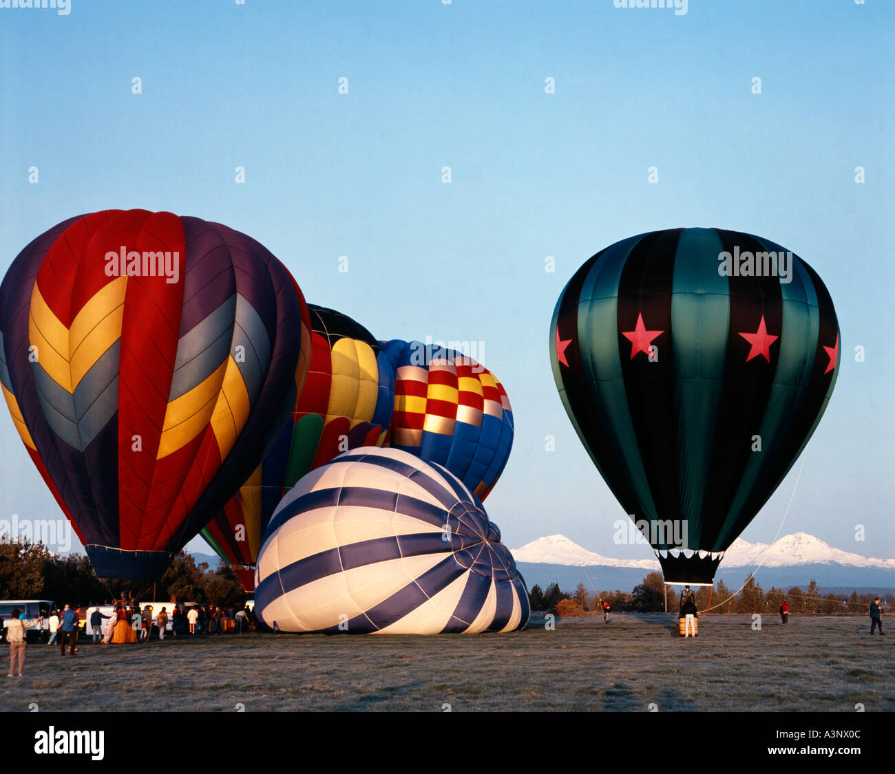 Hot air balloons lift off in early morning at Redmond in Central Oregon with the Cascade mountains as backdrop Stock Photo