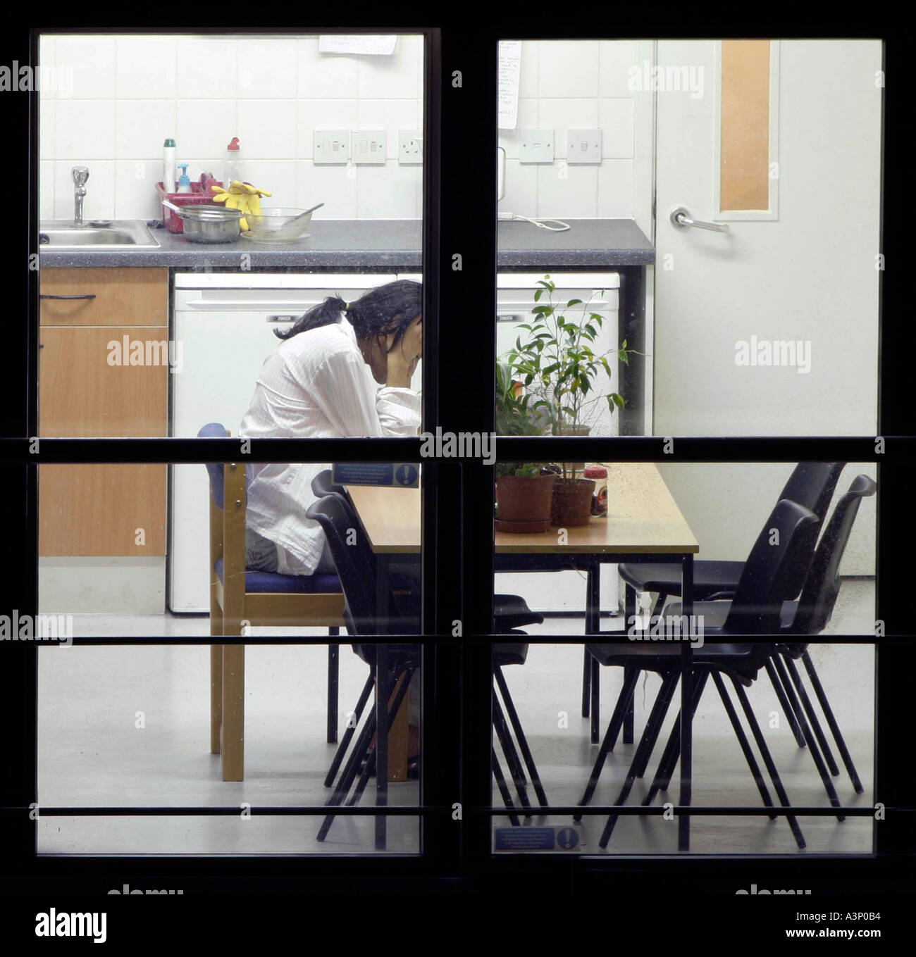Young woman holding her head over a kitchen table Stock Photo
