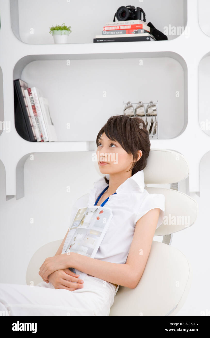 A young woman sitting on sofa holding books Stock Photo - Alamy