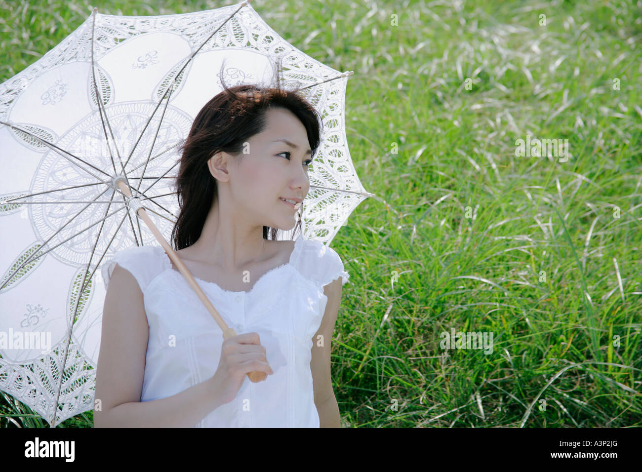A young woman sitting on grass field Stock Photo - Alamy