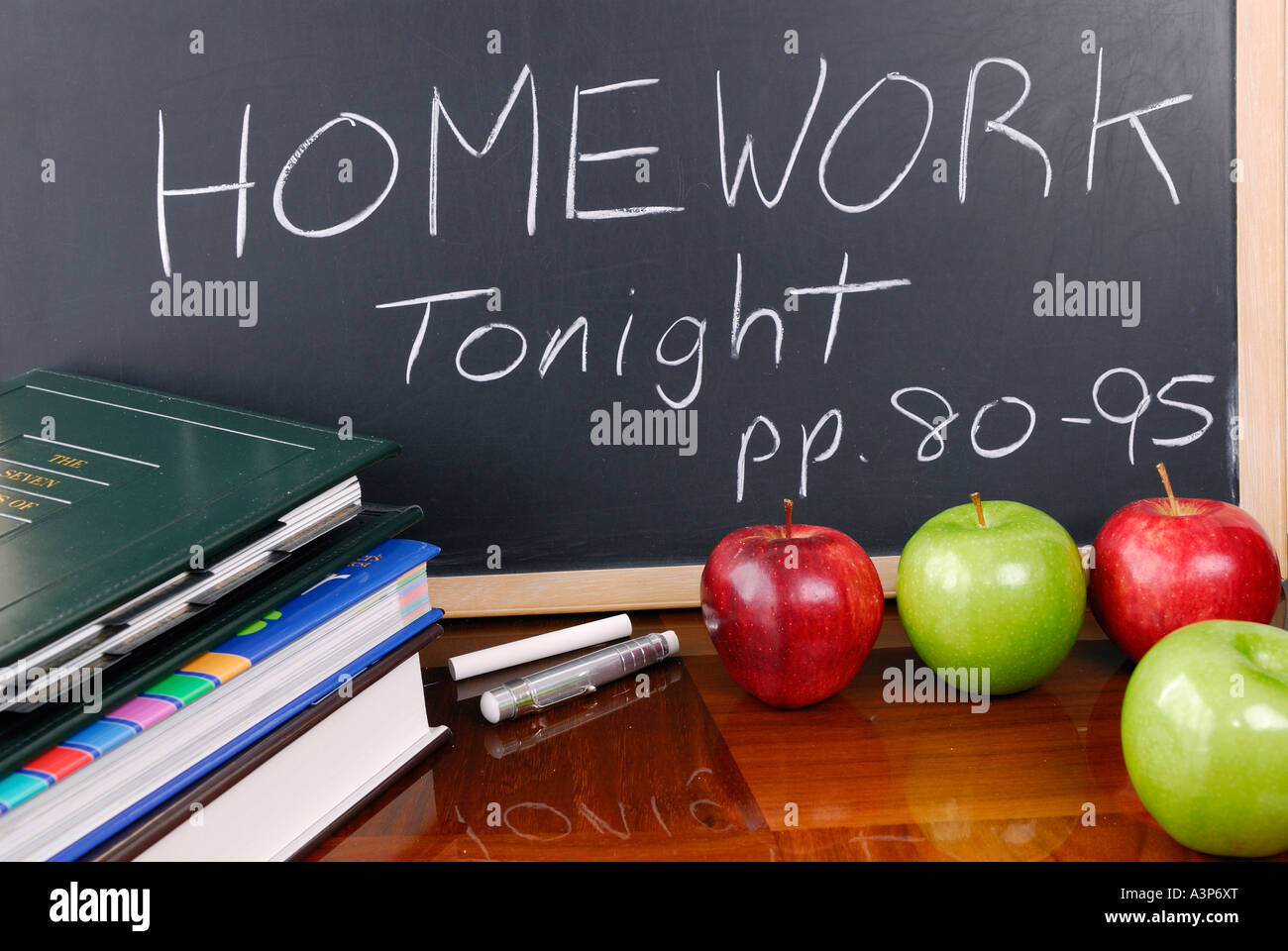Notice on blackboard ofschool homework assignment with books and apples Stock Photo