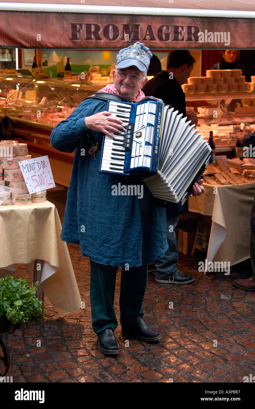 Frenchman playing accordion outside cheese shop paris france Stock Photo