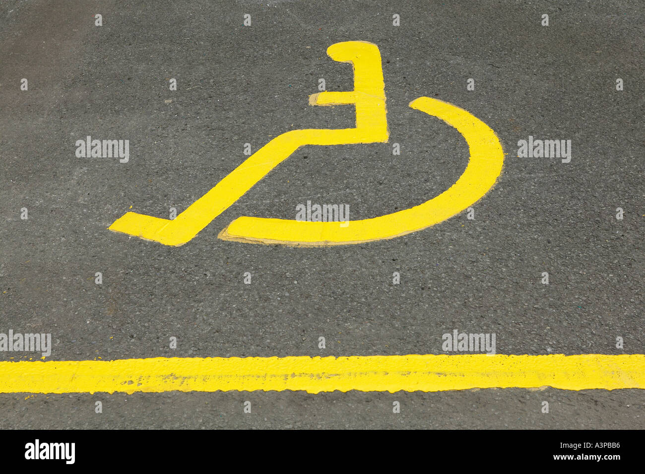PAINTED ICON OF YELLOW WHEEL CHAIR IN DISABLED PARKING BAY Stock Photo