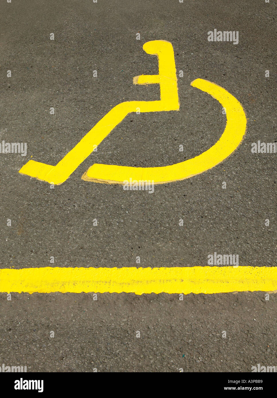 PAINTED ICON OF YELLOW WHEEL CHAIR IN DISABLED PARKING SPACE Stock Photo