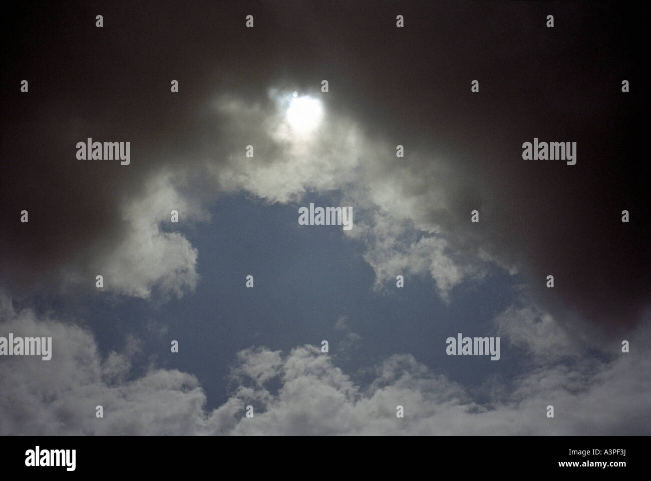 Sun shining through dark clouds Stock Photo