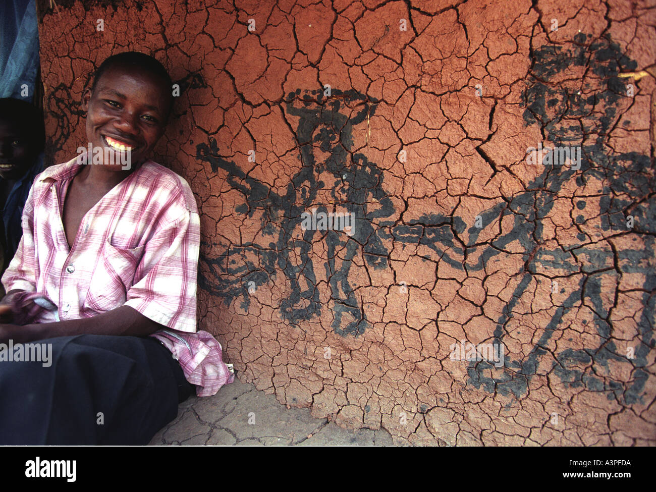 Child in front of mud hut with war paintings on the wall Northern Uganda LRA Lord s Resistance Army Stock Photo