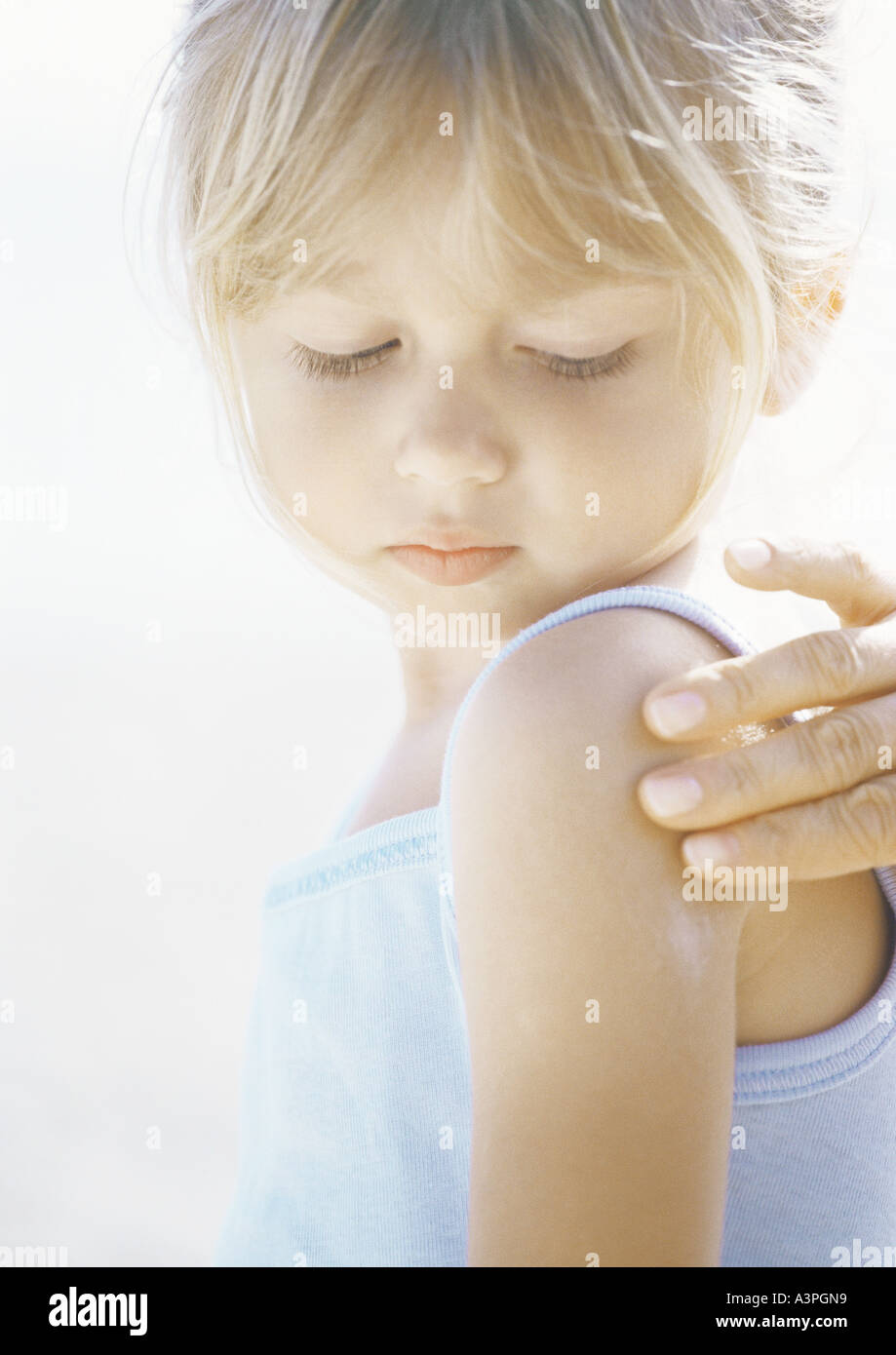 Girl having sunscreen applied to shoulder Stock Photo