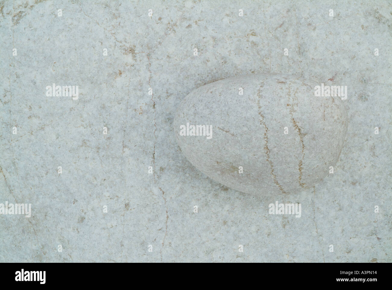 Small oval white pebble on a larger white rock in an abstract pattern Portugal beach EU Stock Photo