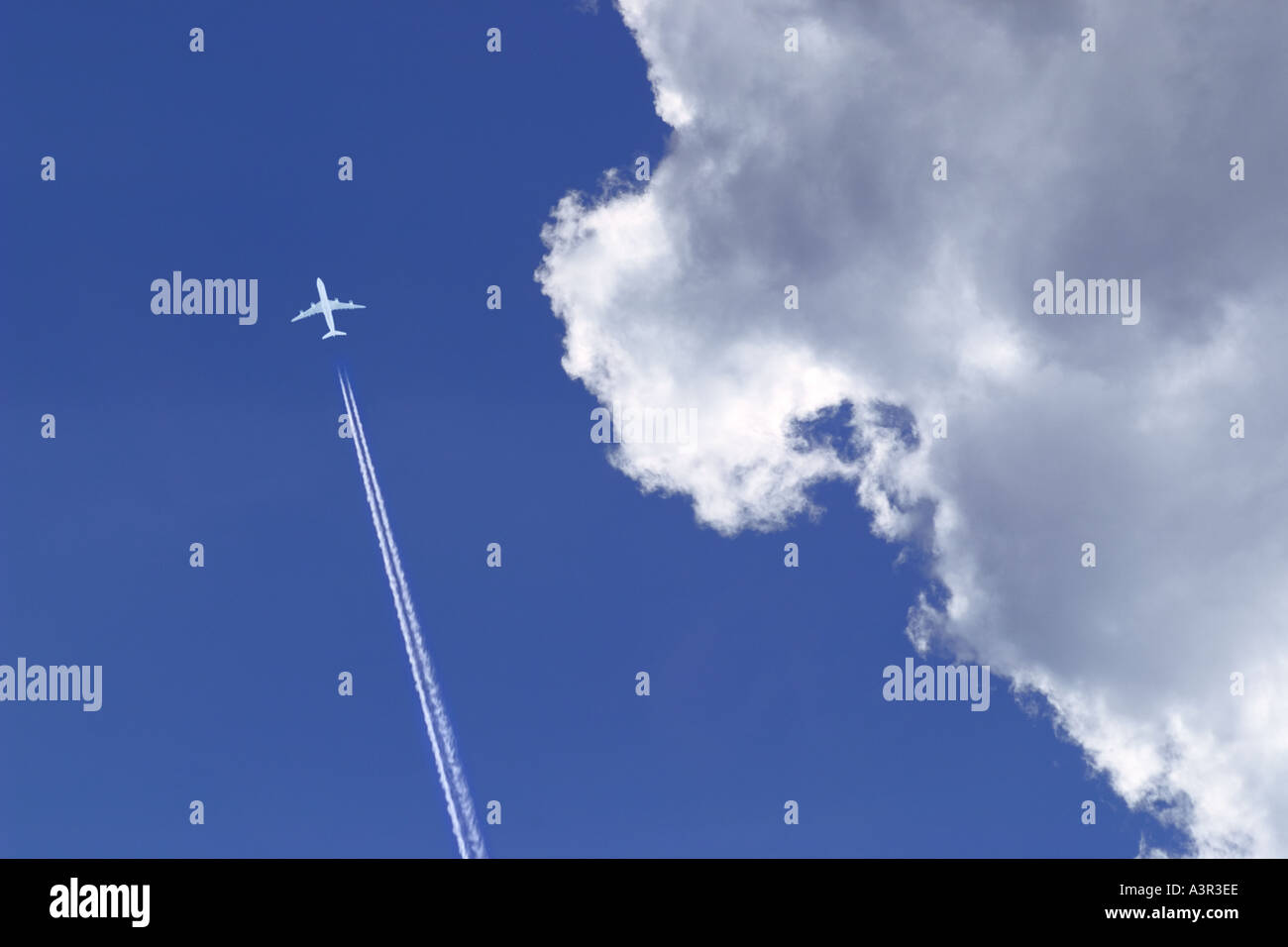 white passenger airplane with vapor trail in blue sky Stock Photo
