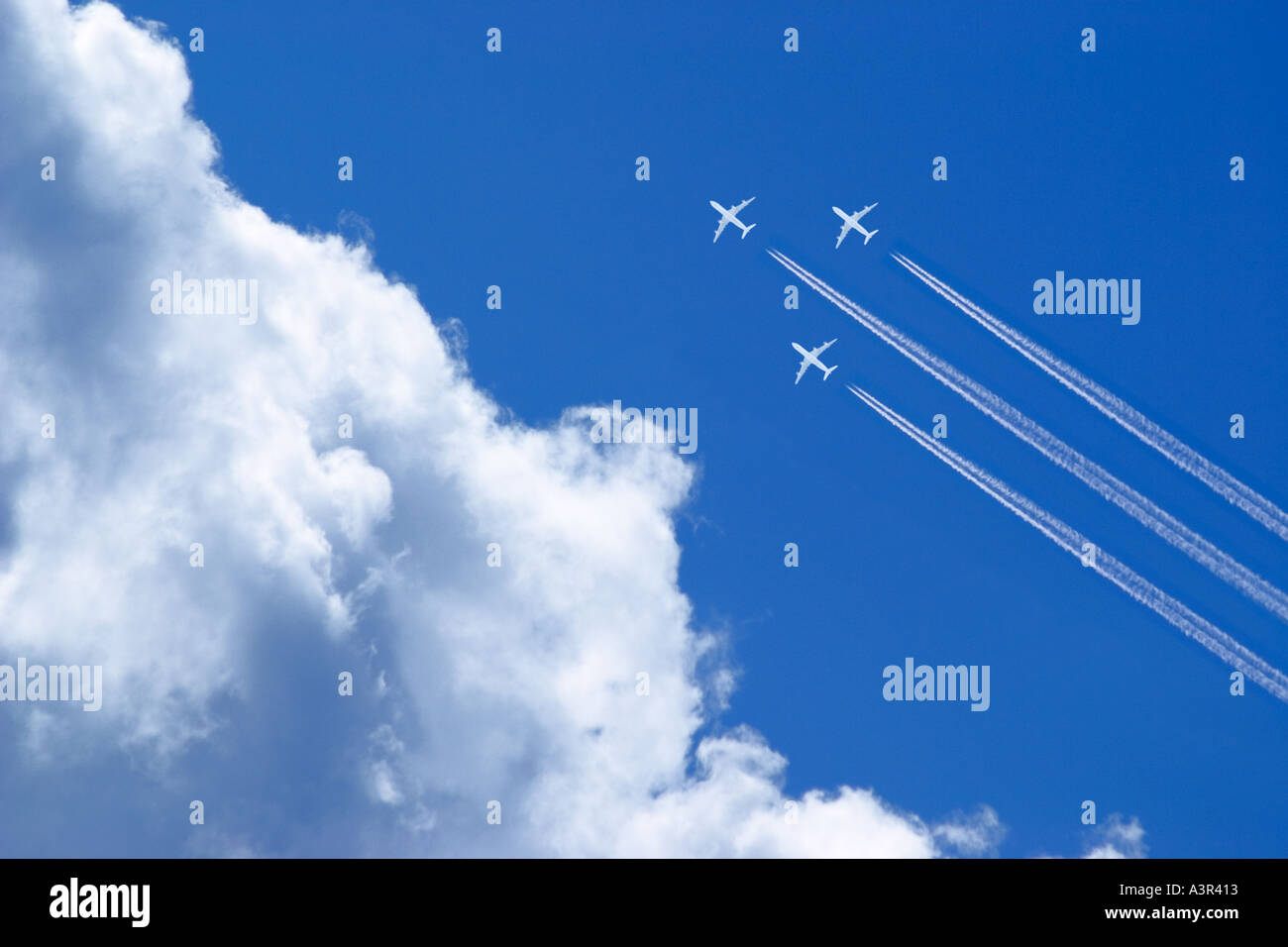 three white passenger airplanes with vapor trails in blue sky Stock Photo