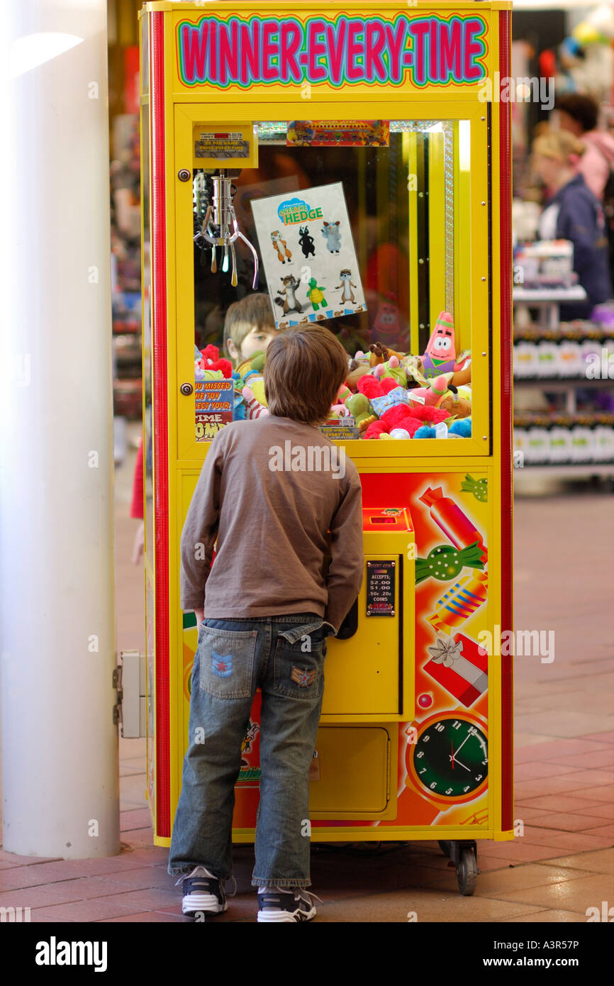 Boy checking out a coin operated lucky dip machine in a shopping mall ...