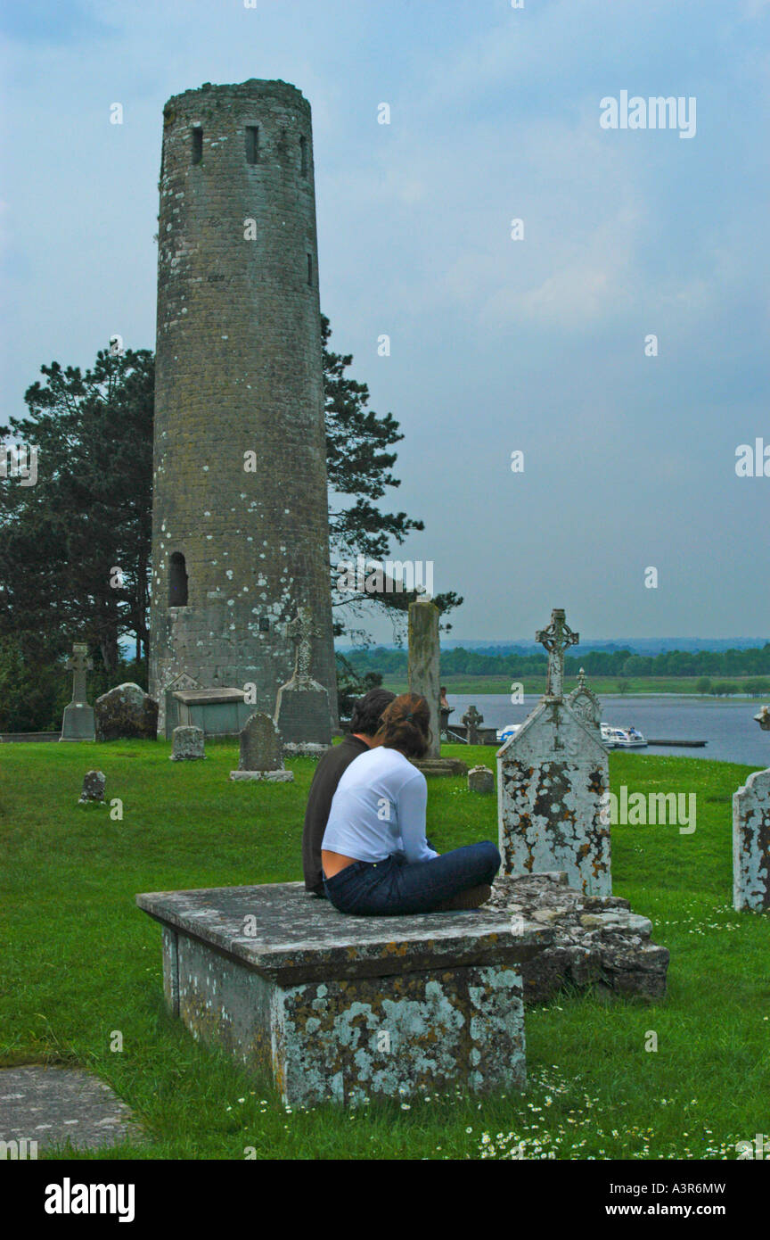 Couple resting on stone slab at ruins of Clonmacnoise Abbey Ireland