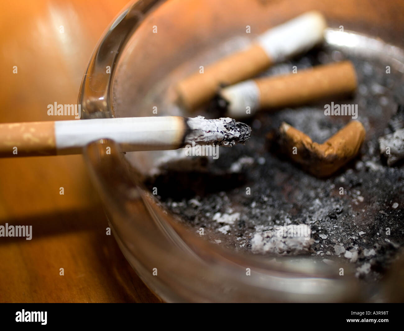 cigarette burning in ashtray Cigarette burning in glass ashtray Stock Photo