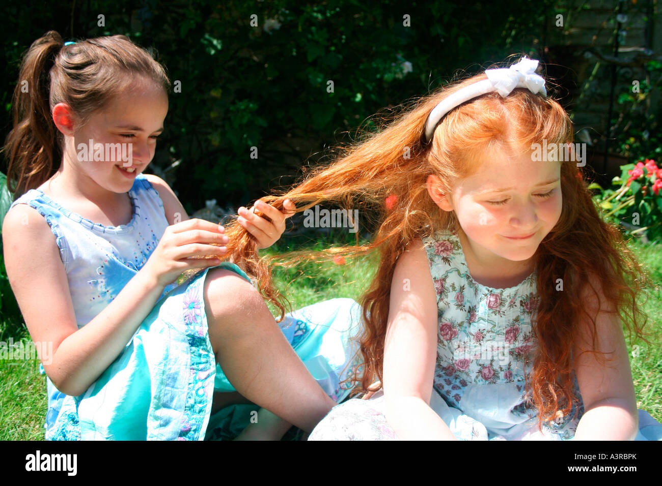 girl plays enviously with hair of redheaded friend Stock Photo