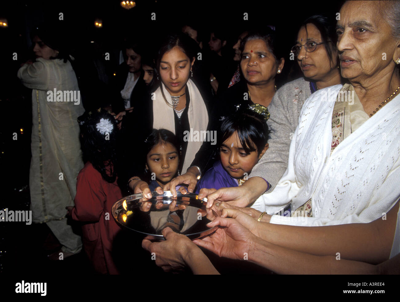 Older women show children how to  perform arti a traditional form of worship to Hindu deities in a temple. Stock Photo