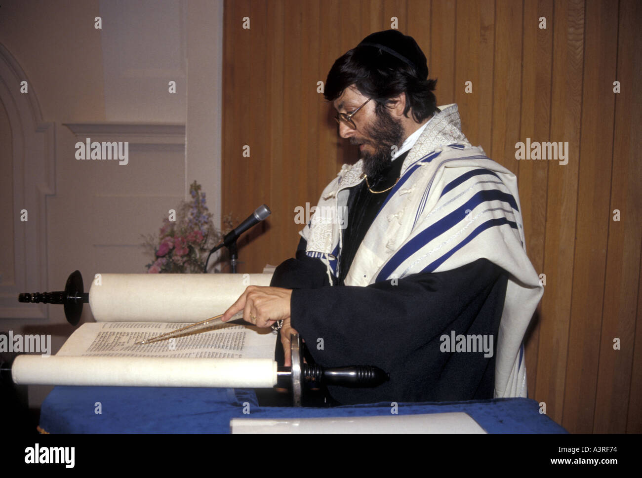 A Rabbi using a yad, or pointer, to read from the torah scrolls in a London reformed synagogue Stock Photo