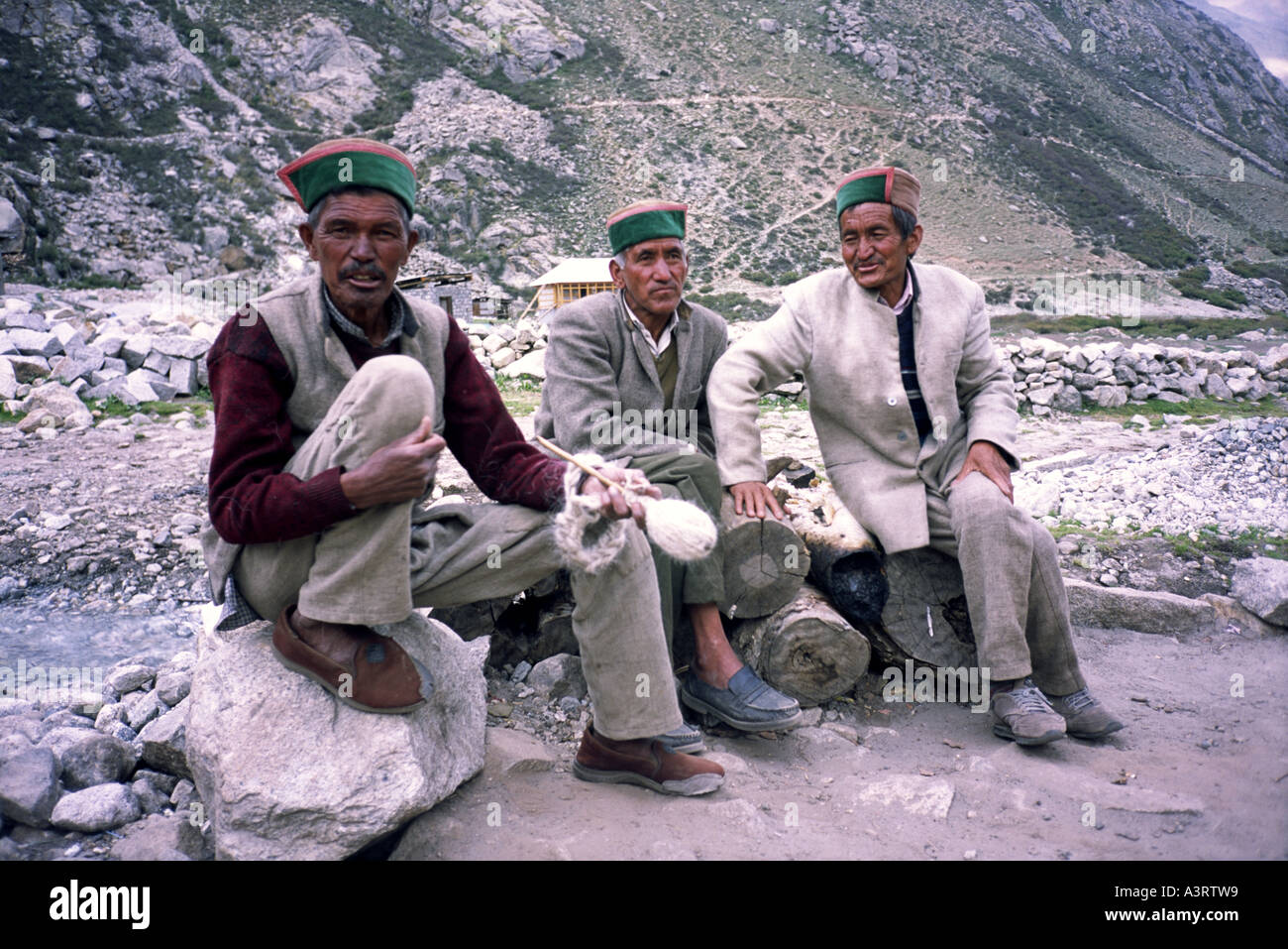 Three local men wearing traditional Kinnauri hats (Thepang) sit in Chitkul village, Sangla Valley, Himachal Pradesh India Stock Photo