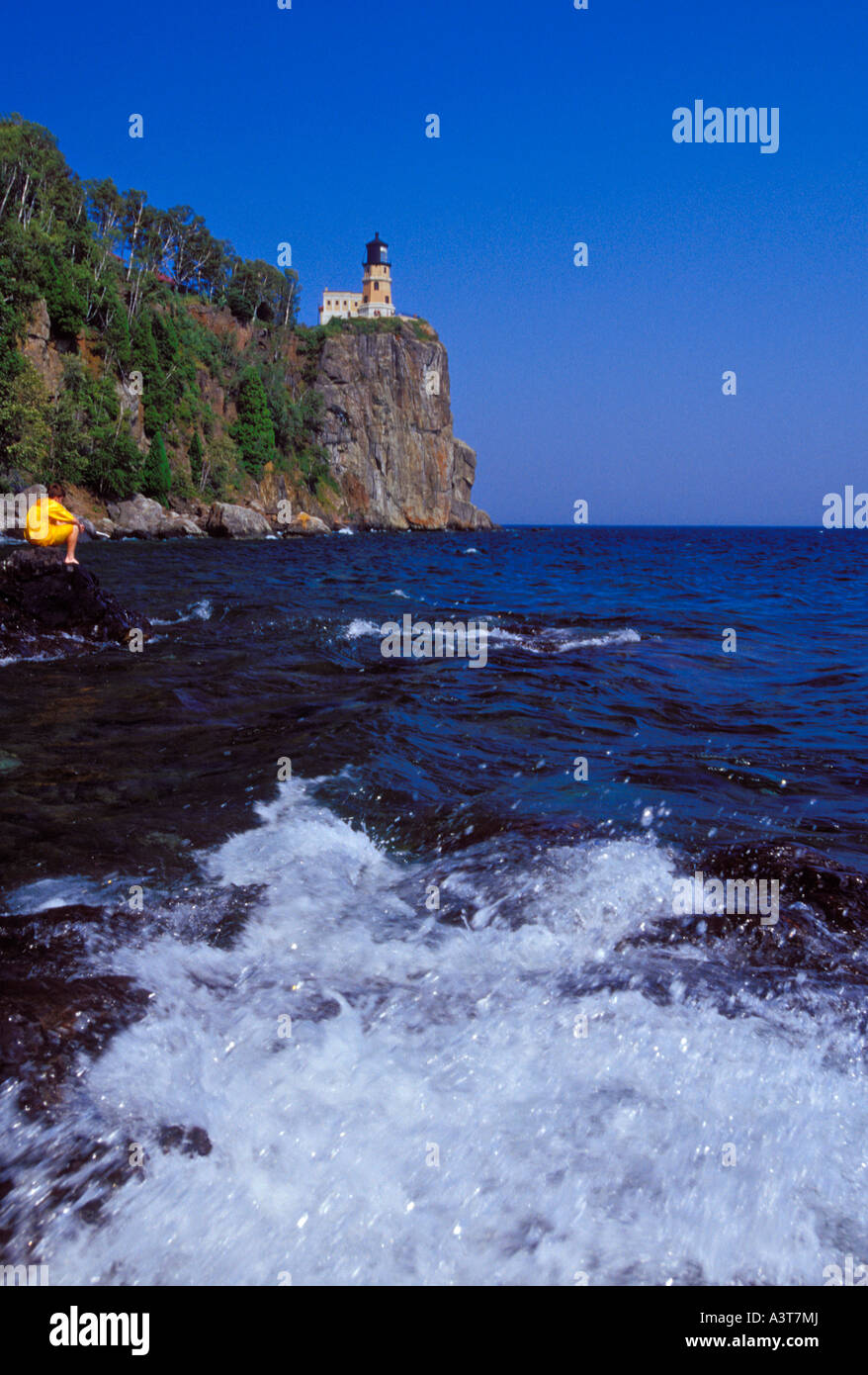 A BOY EXPLORES THE ROCKY SHORE BELOW THE SPLIT ROCK LIGHTHOUSE AT SPLIT ...