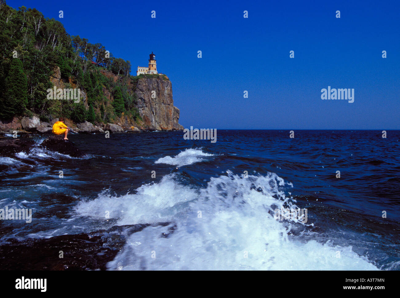A BOY EXPLORES THE ROCKY SHORE BELOW THE SPLIT ROCK LIGHTHOUSE AT SPLIT ...