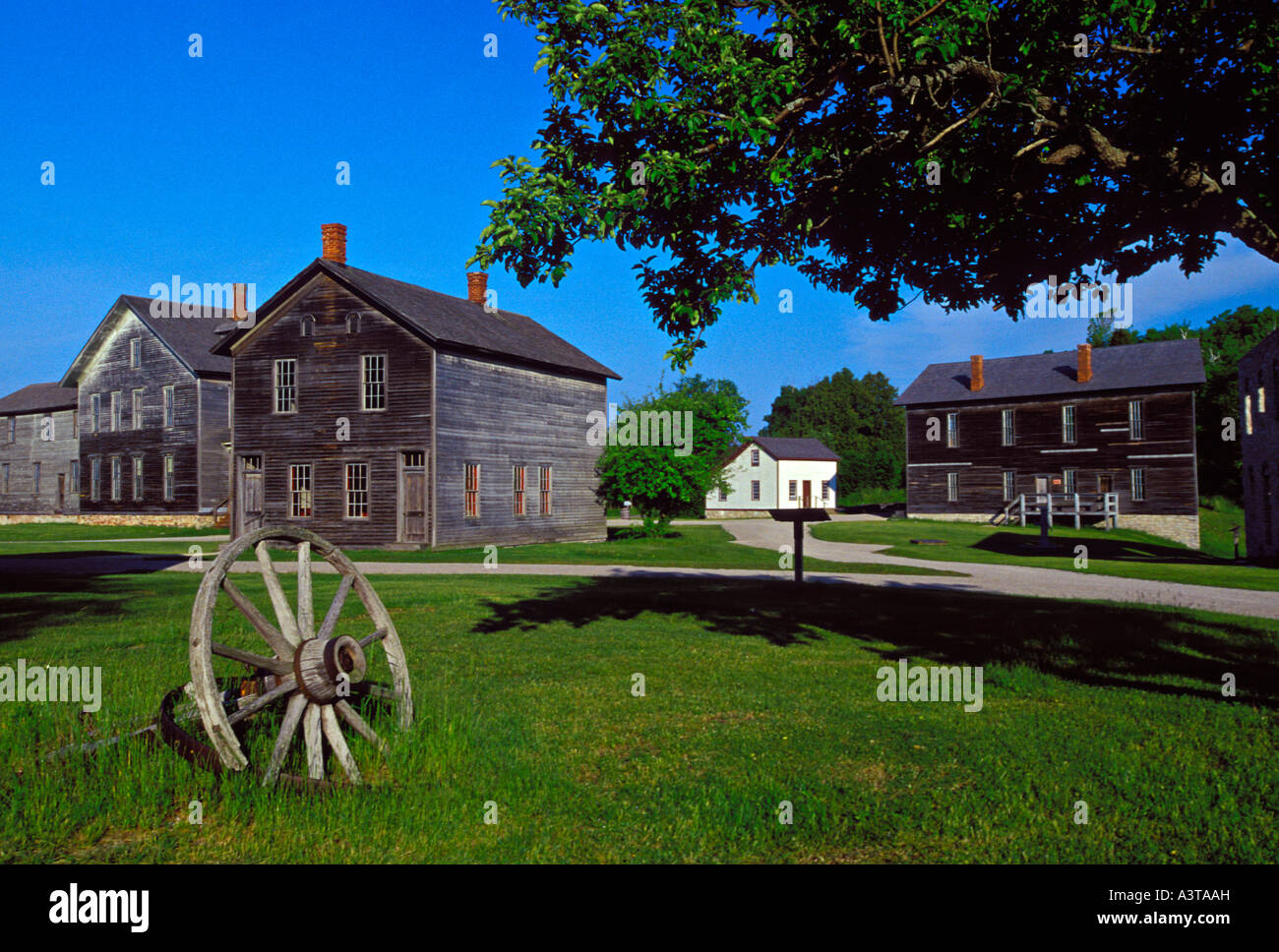 A WAGON WHEEL SITS AMONG NINETEENTH CENTURY BUILDINGS AT FAYETTE STATE HISTORIC PARK ON THE GARDEN PENINSULA Stock Photo