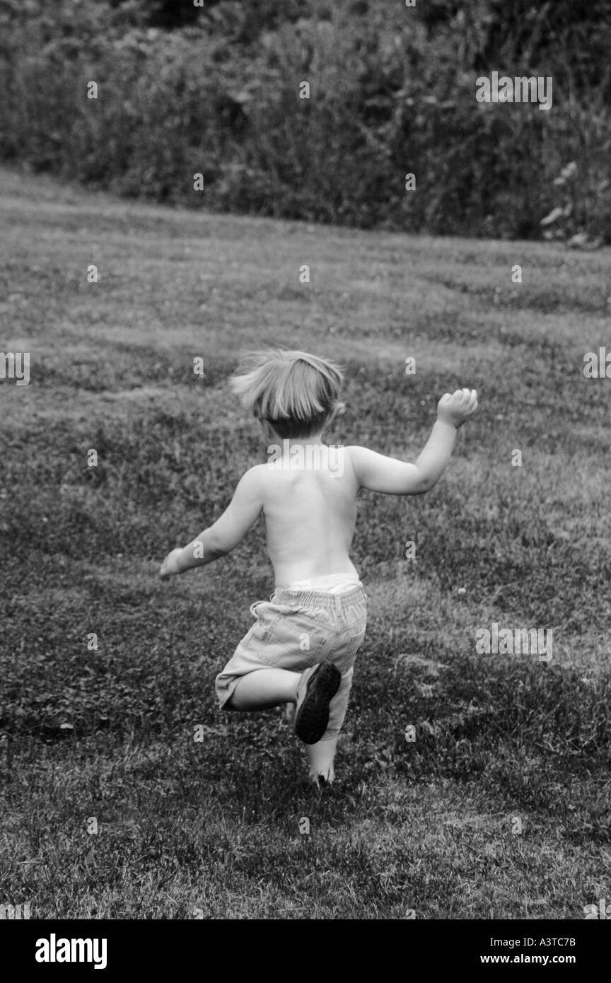 small boy running in grass from back rear Stock Photo - Alamy
