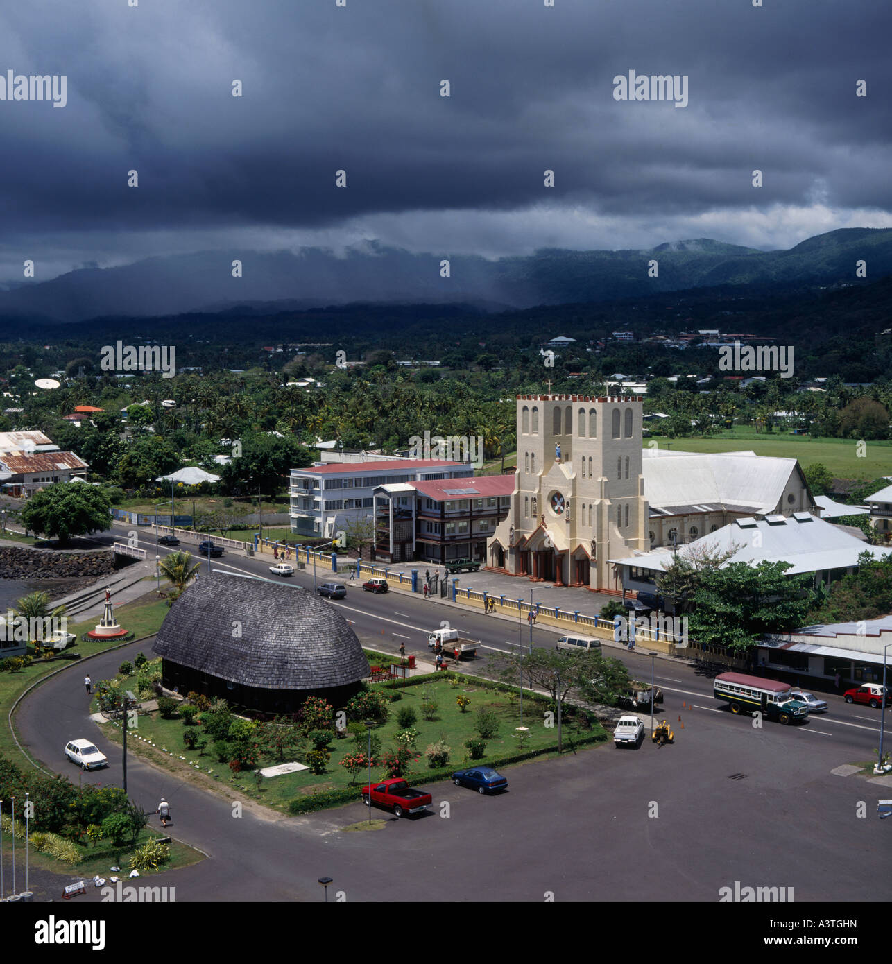 View over main street with Catholic Cathedral Samoan fale housing tourist office bus in Apia town on Upolu Island Western Samoa Stock Photo