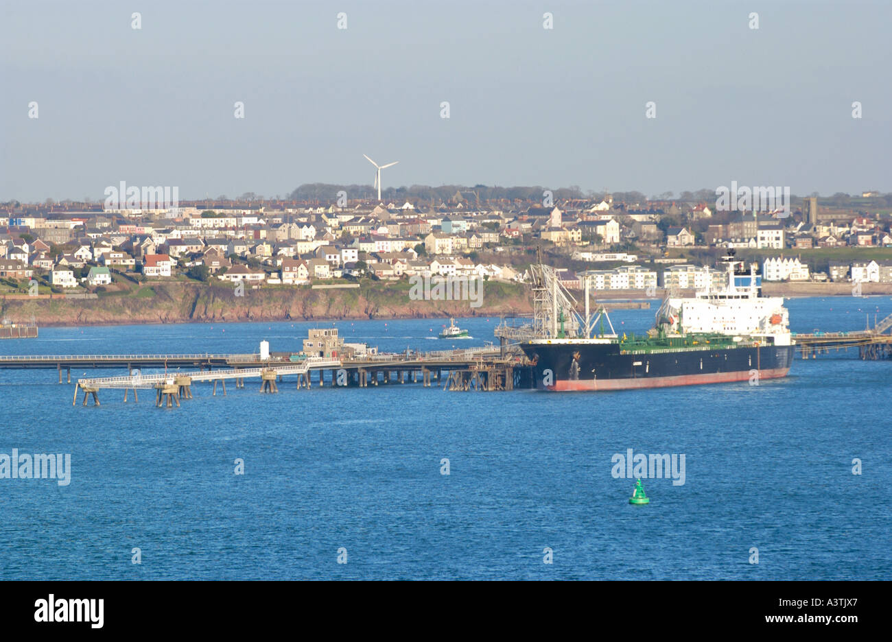 View over oil industry jetty with tanker looking towards the town of Milford Haven Pembrokeshire West Wales UK Stock Photo