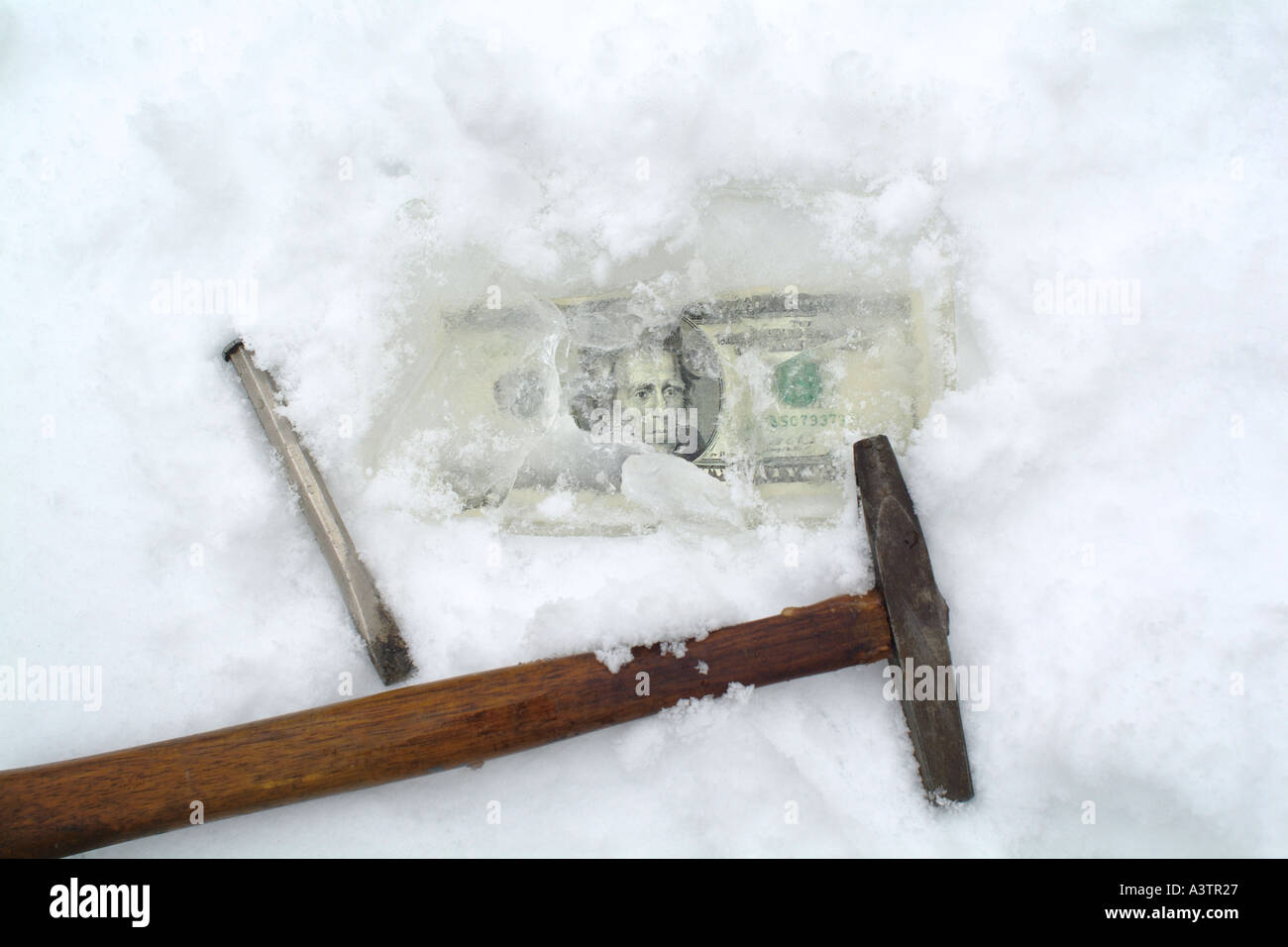 Frozen money with hammer and chisel Stock Photo