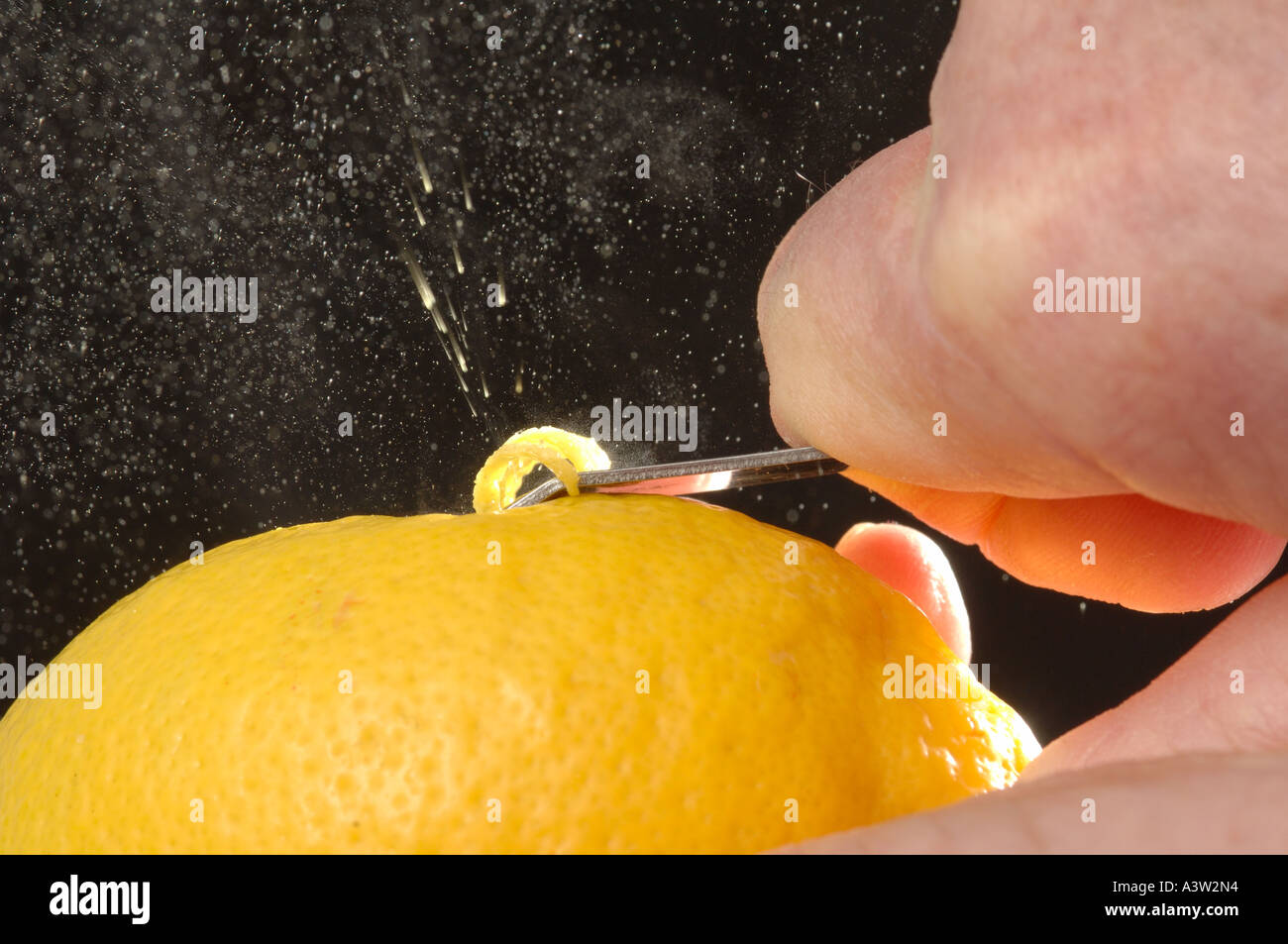 Releasing the zest from the peel of a lemon fruit with a zester Stock Photo