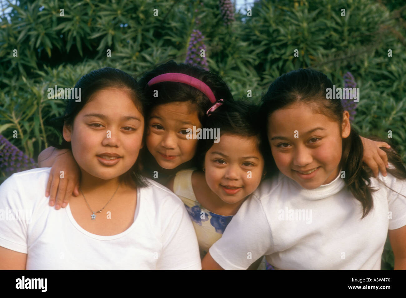 Portrait of 4 Asian American sisters in front of foliage Stock Photo