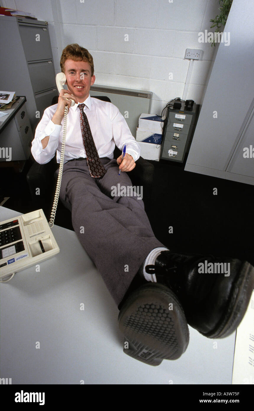 businessman man putting his feet up while answering telephone in office
