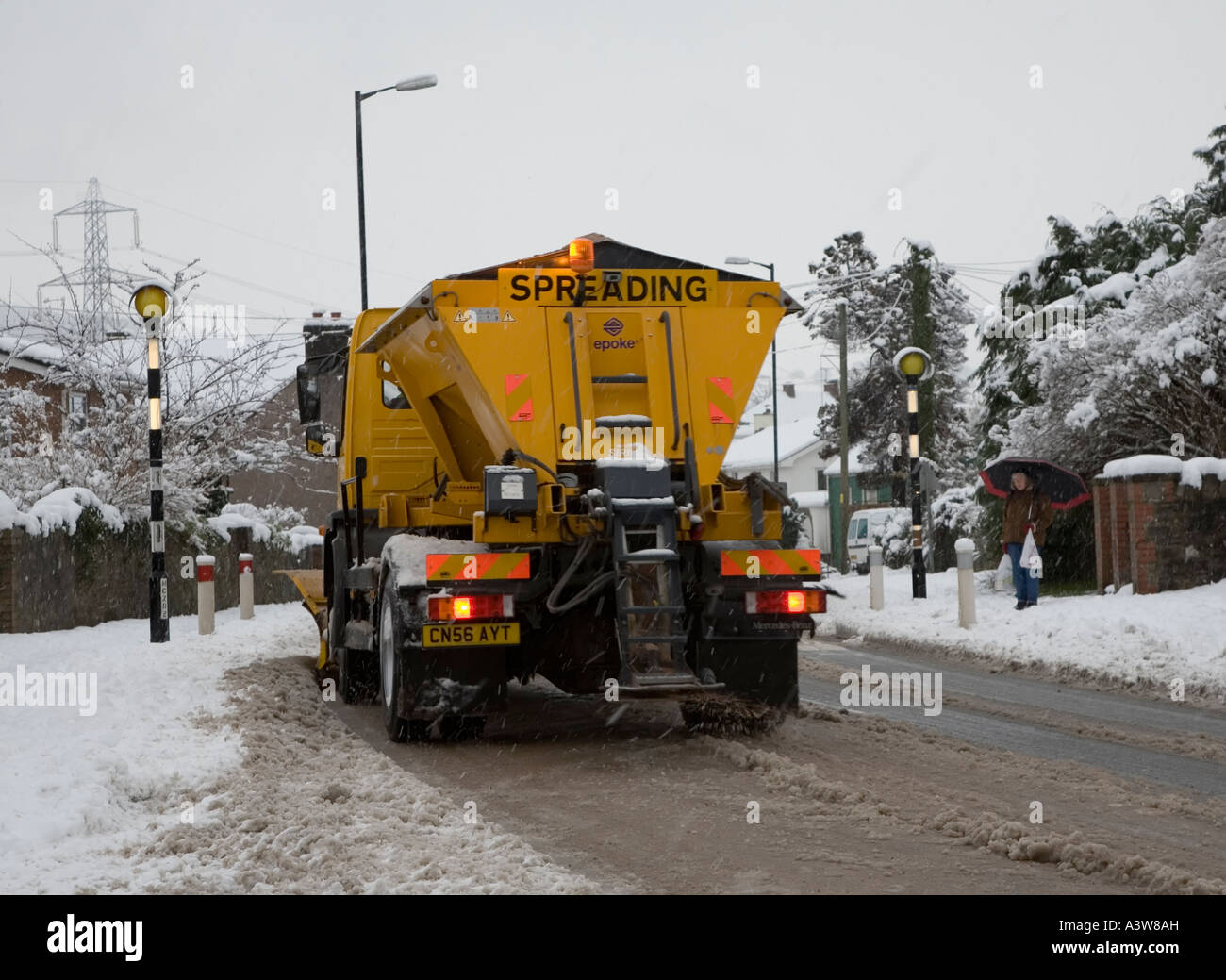 Snowplough spreading grit on road in village of Llanfoist Wales UK Stock Photo