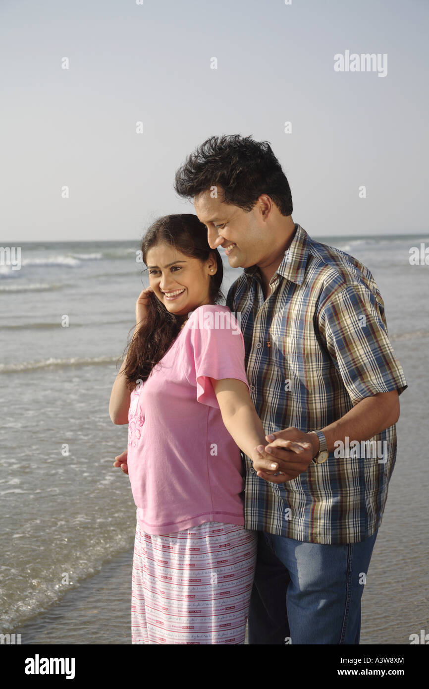 Couple standing on beach lovingly enjoying sun sea and sand Stock Photo