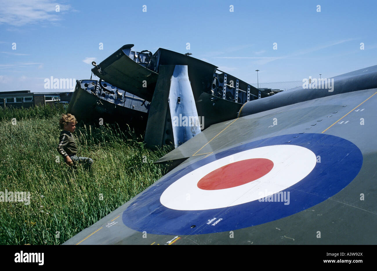 Boy playing in field with parts of RAF aircraft Rhoose Wales UK Stock Photo