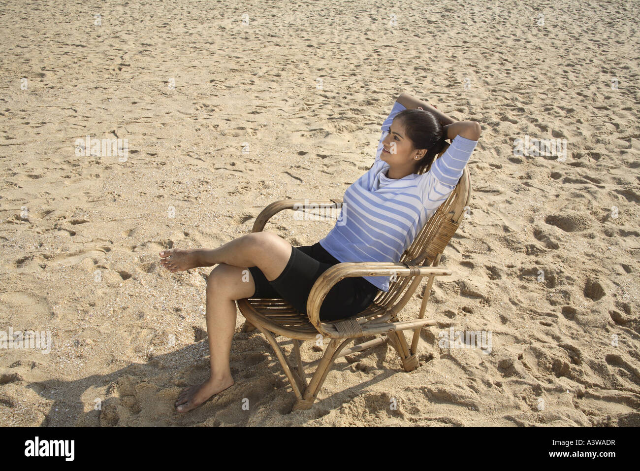 Women on holiday relaxing enjoying sitting in cane chair on beach with sun sand sea Stock Photo