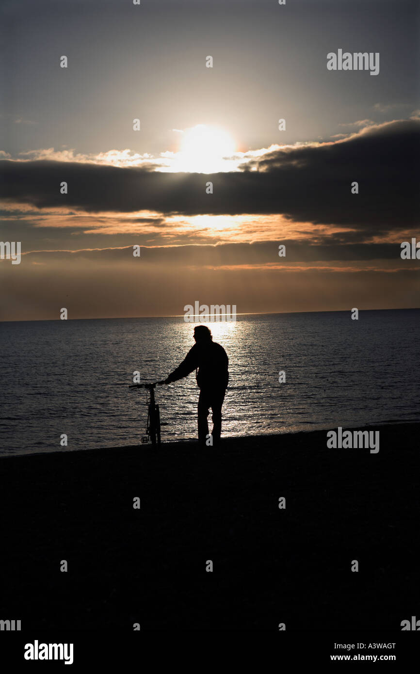 Silhouette of a person with bicycle on the seafront. Stock Photo