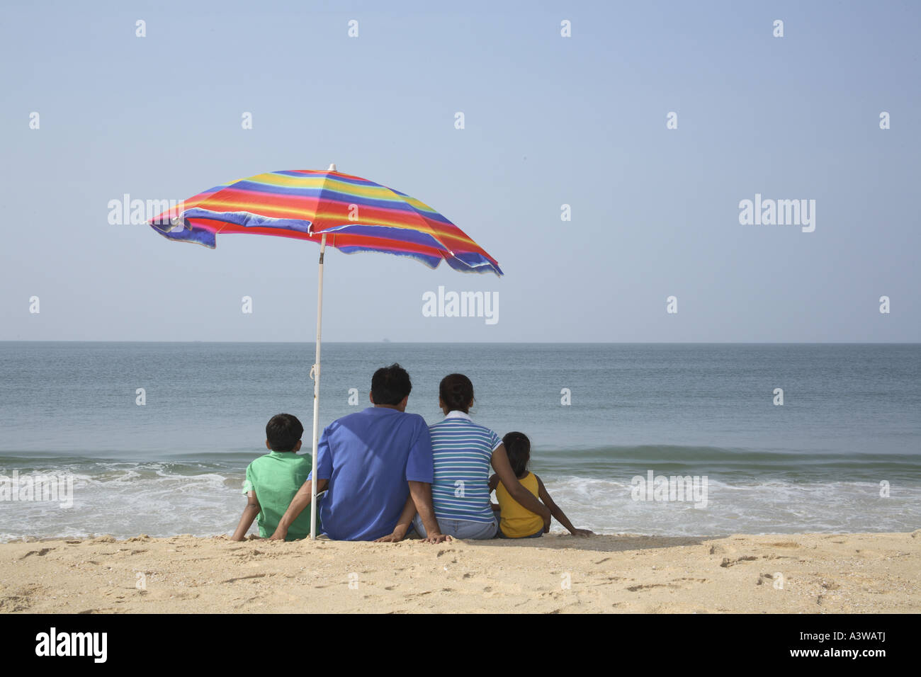 Family Of Four Sitting Below Umbrella On The Beach Lo Ng At The Sea Family Of Four Sitting Below Umbrella On The Beach Lo Ng At The Sea